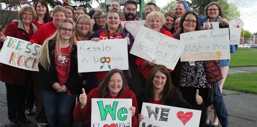 Educators hold signs reading "We love Kessler"